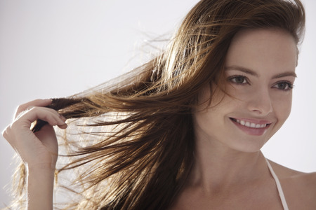 Portrait of young woman with fingers in hairの写真素材