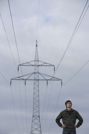 Young man standing under power lineの写真素材