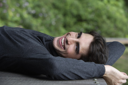 Young man lying back on wooden deckの写真素材