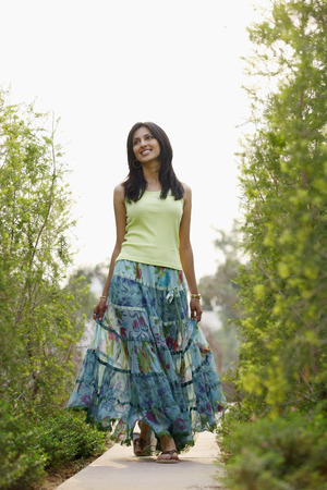 Woman in flowing skirt, walking on pathwayの写真素材