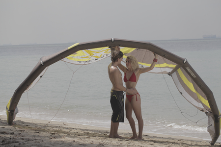 Young couple embracing under a surf kite on the beachの写真素材