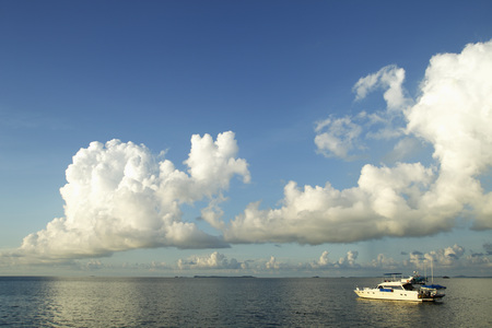 boat in the ocean with clouds and blue sky as backgroundの写真素材