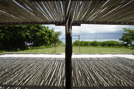 thatched roof casting shadows on the sandの写真素材
