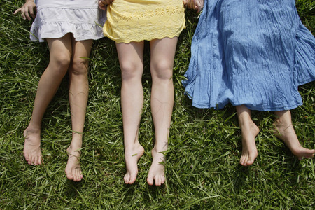 Cropped shot of legs of three teen girls lying on the grassの写真素材