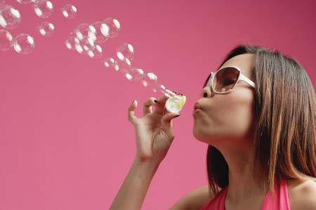 Woman wearing sunglasses, blowing bubblesの写真素材