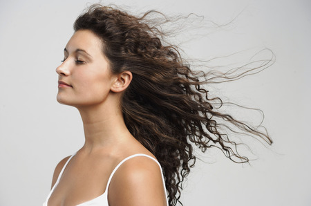 Woman with wind blowing in face, eyes closedの写真素材