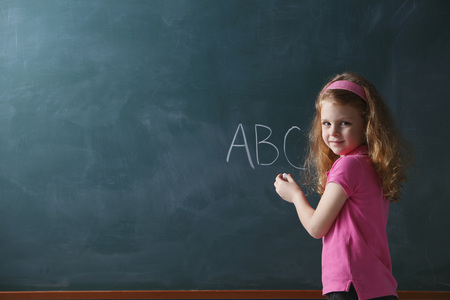 Young girl writing abc on chalk boardの写真素材