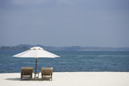 two lounge chairs on white sand beachの写真素材