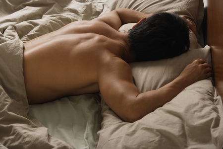 Back view of man sleeping in bed.の写真素材