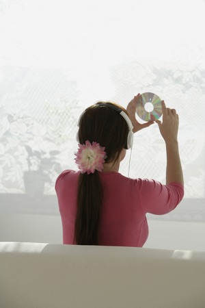 Woman looking at disc while listening to music.の写真素材