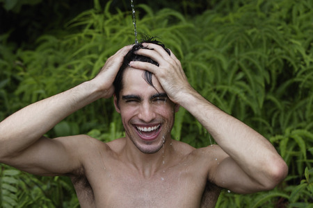 Young man having shower outdoorsの写真素材