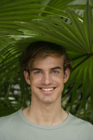 portrait of young man under tropical tree