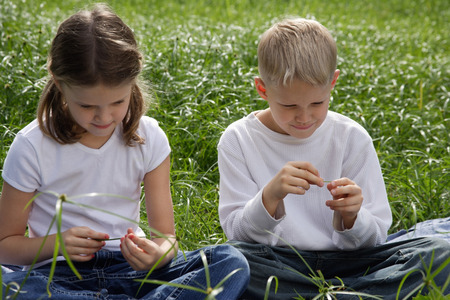 brother and sister sitting on grass in parkの写真素材