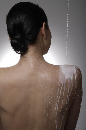 Milk being poured down a woman's backの写真素材