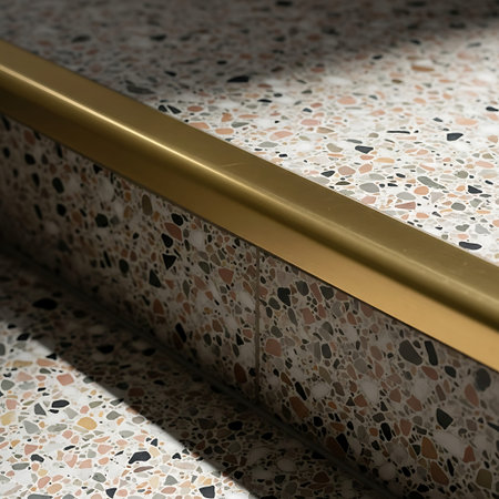 Close-up of Worn Terrazzo Staircase Landing Highlighting Rounded Brass Nosing Detail.