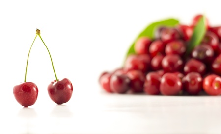 A pair of cherries withgroup of cherries in the background on the wihte backgroundの写真素材