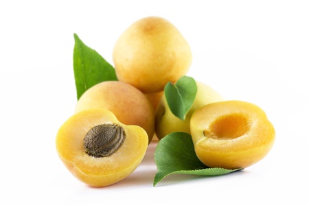 Half of apricot with a pit and leafs and mound of apritocs on a white backgroundの写真素材