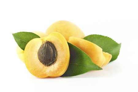 Half of apricot with a pit and leafs on a white backgroundの写真素材