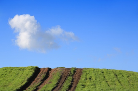 Dirt tracks up the hill, sloping upward to the skyの写真素材
