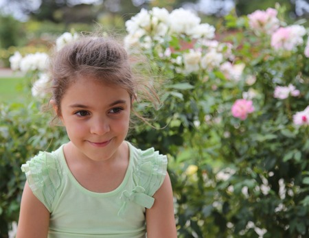 Beautiful girl with flower bushes in the backgroundの写真素材