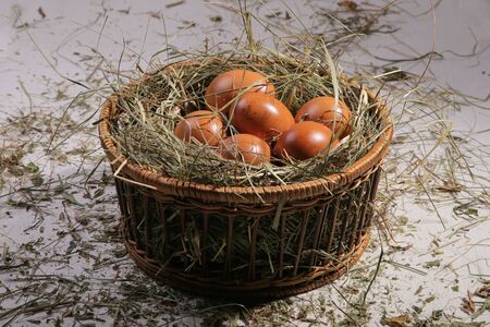 Six eggs lying on a hay in a basket. Easter or village theme.の写真素材
