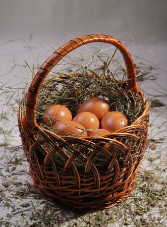 Six eggs lying on a hay in a basket. Easter or village theme.の写真素材