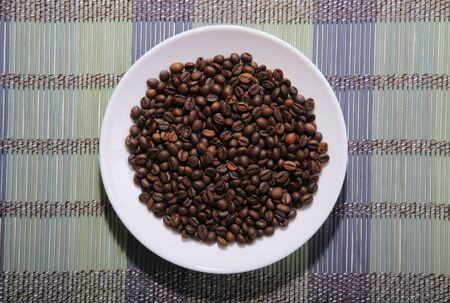 A scattering of coffee beans on a plate. Bamboo mat.の写真素材