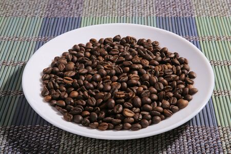 A scattering of coffee beans on a plate. Bamboo mat.の写真素材
