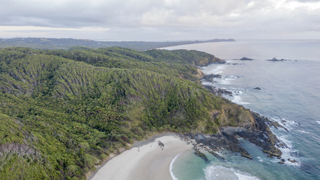 bay beach cliffs and forest at sunrise aerial photoの写真素材