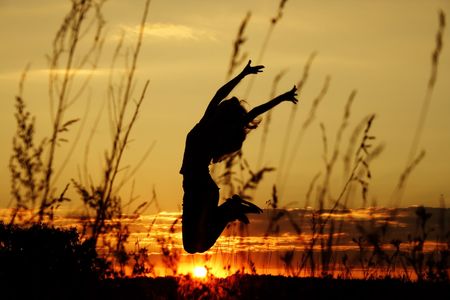 dark silhouette of the jumping girl on a background of a declineの写真素材