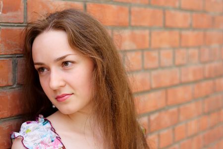 portrait of the sad girl on a background of a brick wallの写真素材