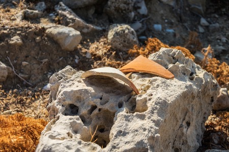 fragments of ancient pottery lying on sandstone under the sun