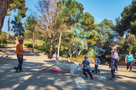 March 2017, Barcelona, Spain - Man blowing giant bubbles in the Guel park. Street performer inflating huge bubbles for kids.のeditorial素材