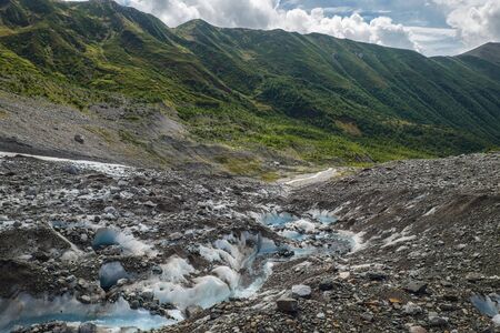 Ice spring on a glacier tongue flow down and transfoms to river Adishchala in mountains of Svaneti Georgiaの写真素材