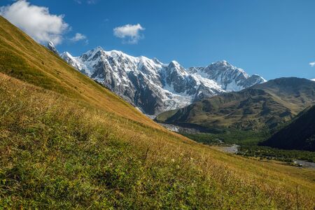Huge beautiful snowy mountains on a sunny day while hiking in Svaneti Georgiaの写真素材