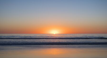 sunset at the sea coast waves no cloud symmetricの写真素材