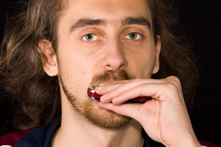 Full face portrait of man playing harmonica on black background