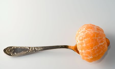 Metal teaspoon holding a half of tangerine from aboveの写真素材