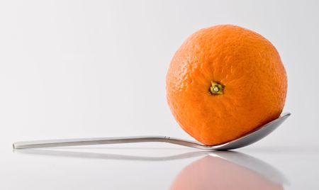 Metal tea-spoon with tangerine in it, reflective surface and shadowsの写真素材