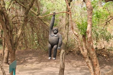 wooden gorilla hanging on the tree by one hand 