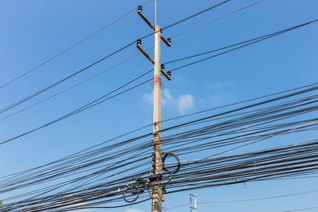 Electric pole power lines and messy wires with blue sky,Thailandの写真素材
