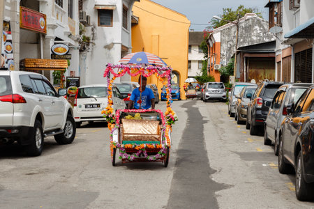 George Town, Penang, Malaysia - November 26, 2017: Rickshaw driver is driving down the street in...