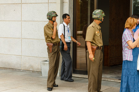 Panmunjom, North Korea - July 30, 2014: North Korean soldiers guard tourists on the border with...