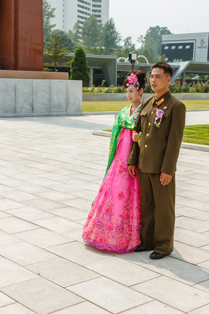 Pyongyang, North Korea - July 29, 2014: Young Korean couple in Victorious Fatherland Liberation War Museum. Newlyweds are photographed against the background of the museum.のeditorial素材