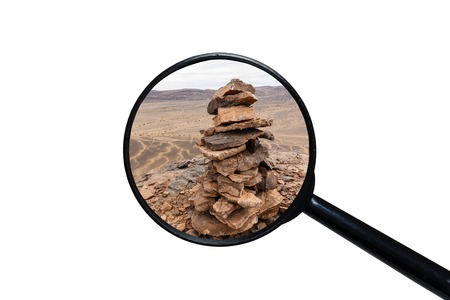 Stone pile mark on the mountain peak, view through a magnifying glass, white background