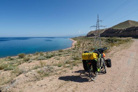 traveler's bike with bags stand on the road near Issyk-Kul Lake, landscape, Kyrgyzstan, tourist bikeの写真素材