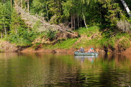 Tuzha, Russia - June 15, 2019: fishermen catch fish on a rubber boat on a forest river. Pizhma River.のeditorial素材