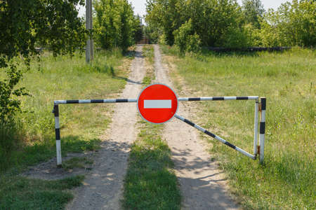 Closed barrier and prohibition sign on a rural road. No entry.