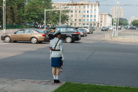 Pyongyang, North Korea - July 29, 2014: A girl policeman regulates traffic at a crossroads in Pyongyang. Pyongyang symbol.のeditorial素材