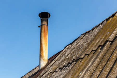 Chimney pipe on the roof of the house against the blue sky.の写真素材